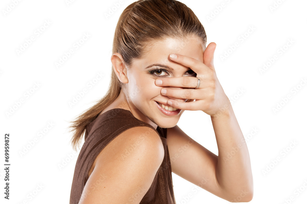 ashamed smiling young woman looking through her fingers ashamed smiling young woman looking through her fingers