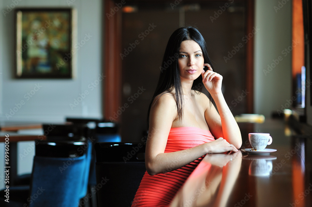 Pretty young woman sitting in a cafe with a cup of coffee Pretty young woman sitting in a cafe with a cup of coffee