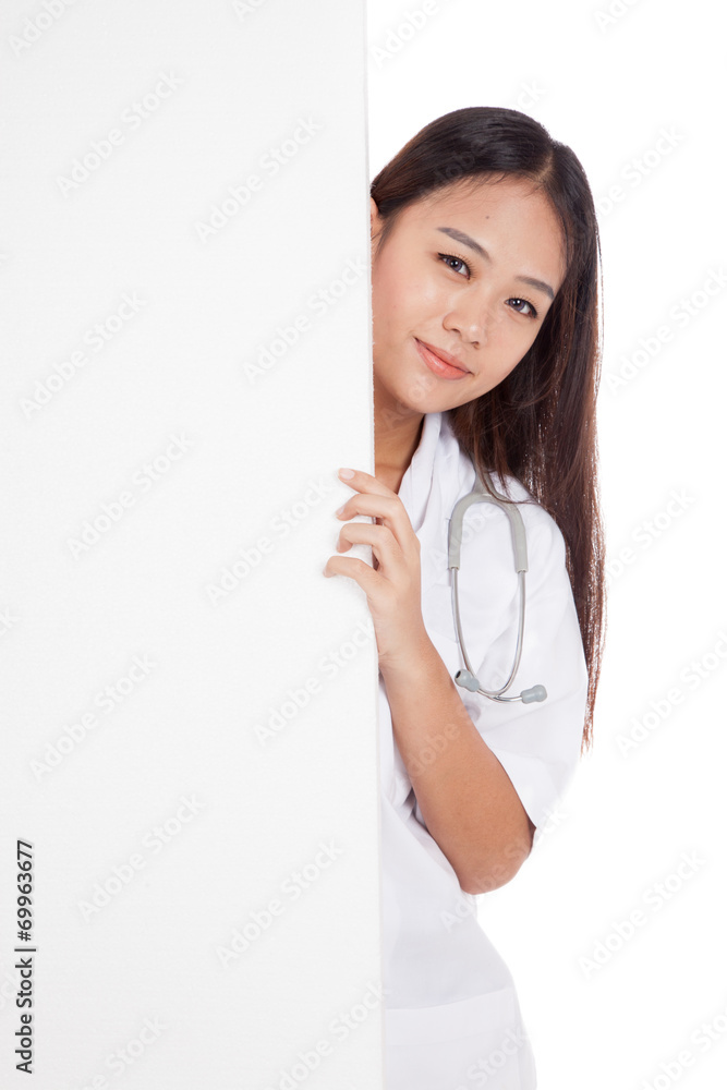 Young Asian female doctor peeking from behind blank sign billboa Young Asian female doctor peeking from behind blank sign billboa