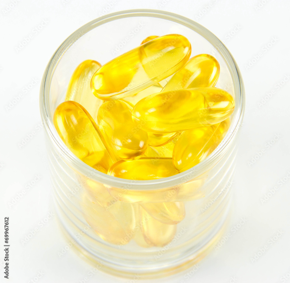 Healthy vitamin glass : yellow oil pills in translucent glass Healthy vitamin glass : yellow oil pills in translucent glass