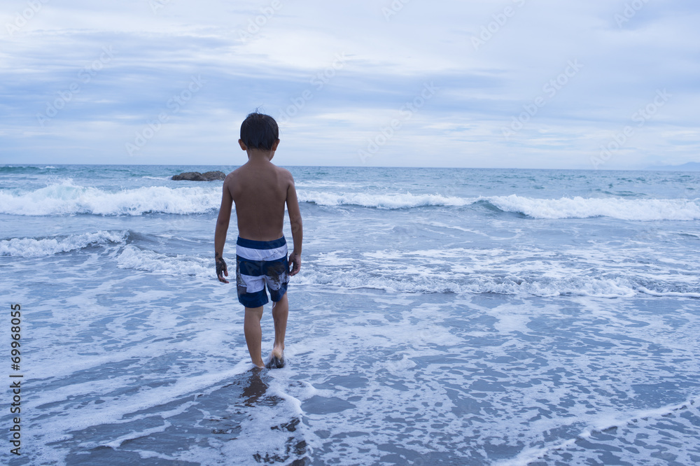 Lonely boy walking towards the sea Lonely boy walking towards the sea