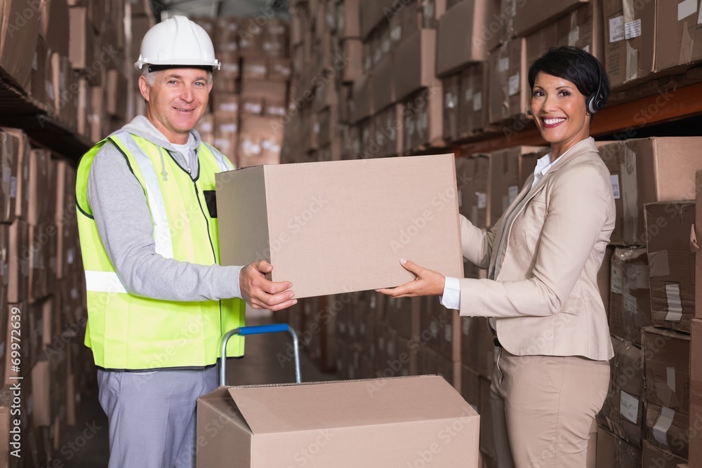 Warehouse worker and manager passing a box Warehouse worker and manager passing a box