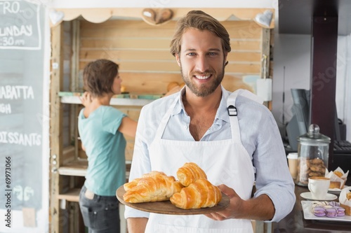 Handsome waiter holding tray of croissants