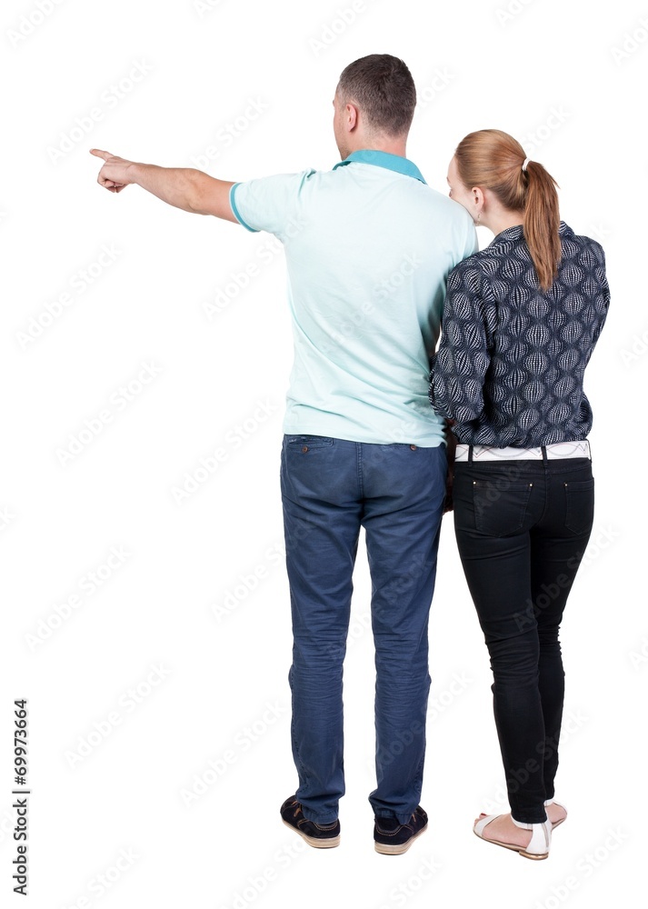 young couple pointing at wal Back view young couple pointing at wal Back view