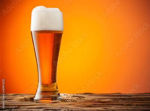 Glass of beer on wood with orange background