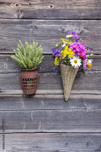 two wicker baskets with flowers and wheat ears on wall