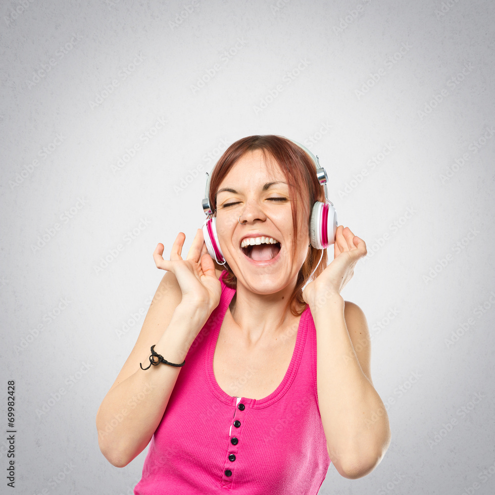 Fototapeta premium Young girl listening music over grey background