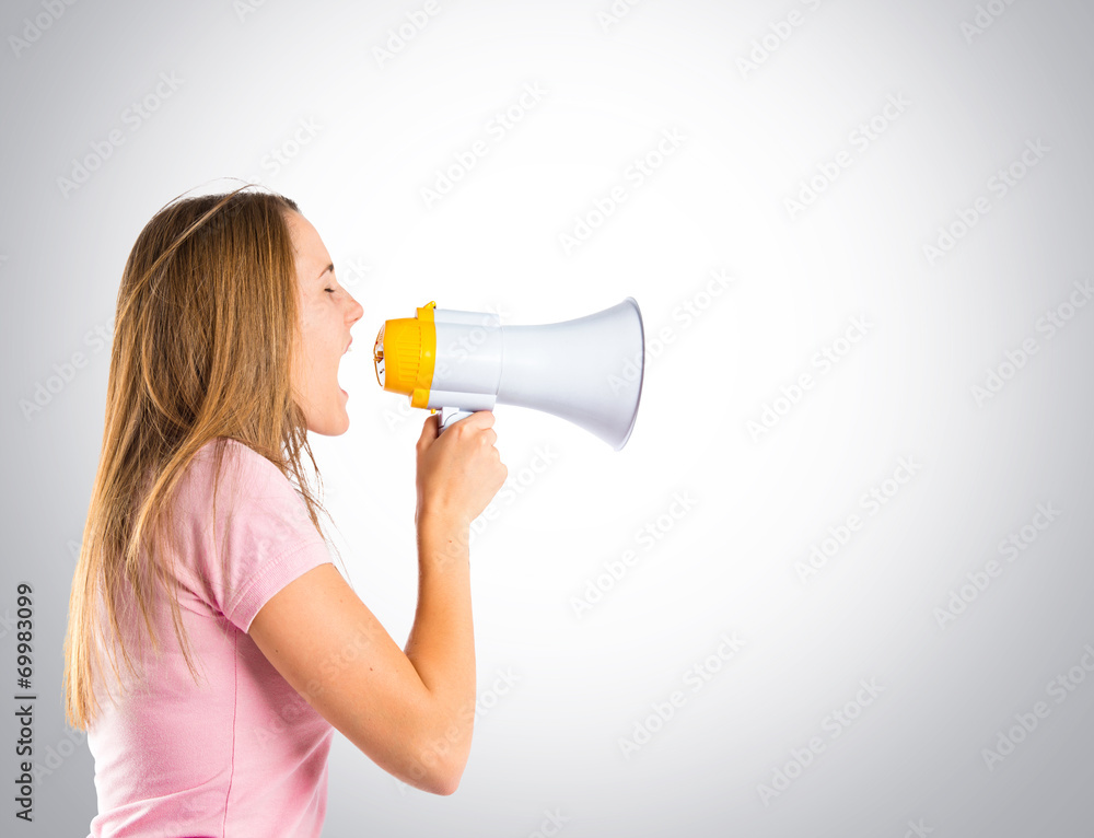 Blonde girl shouting with a megaphone over grey background Blonde girl shouting with a megaphone over grey background