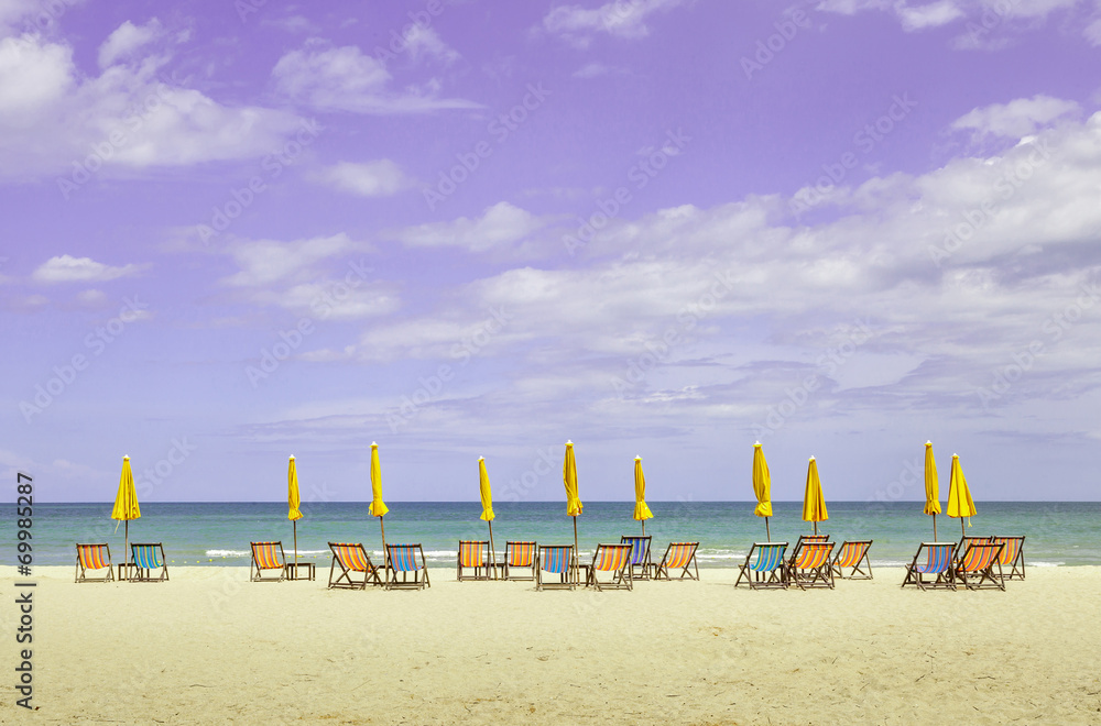 Colorful beach chairs and closed umbrellas on beautiful beach wi Colorful beach chairs and closed umbrellas on beautiful beach wi