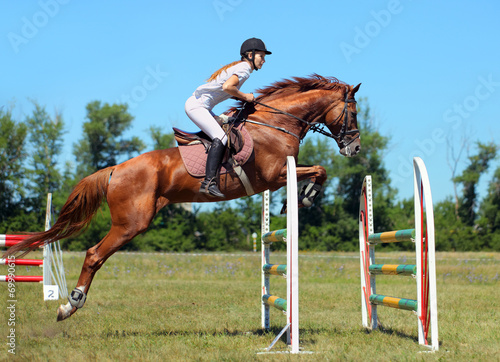 Woman horseback on jumping red chestnut horse