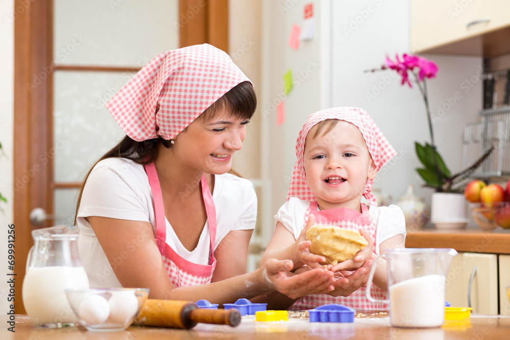 kid girl with her mom making dough in the kitchen