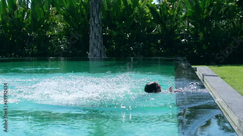 Mother jumping with her son into swimming pool and having fun photo