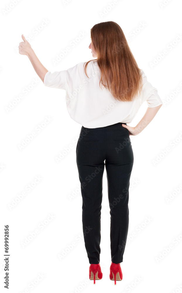 back view of standing young redhead business woman showing thumb back view of standing young redhead business woman showing thumb
