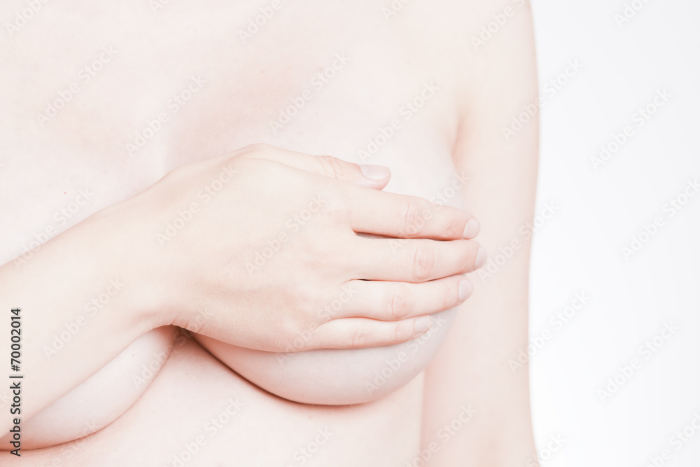adult woman examining her breast for lumps or breast cancer