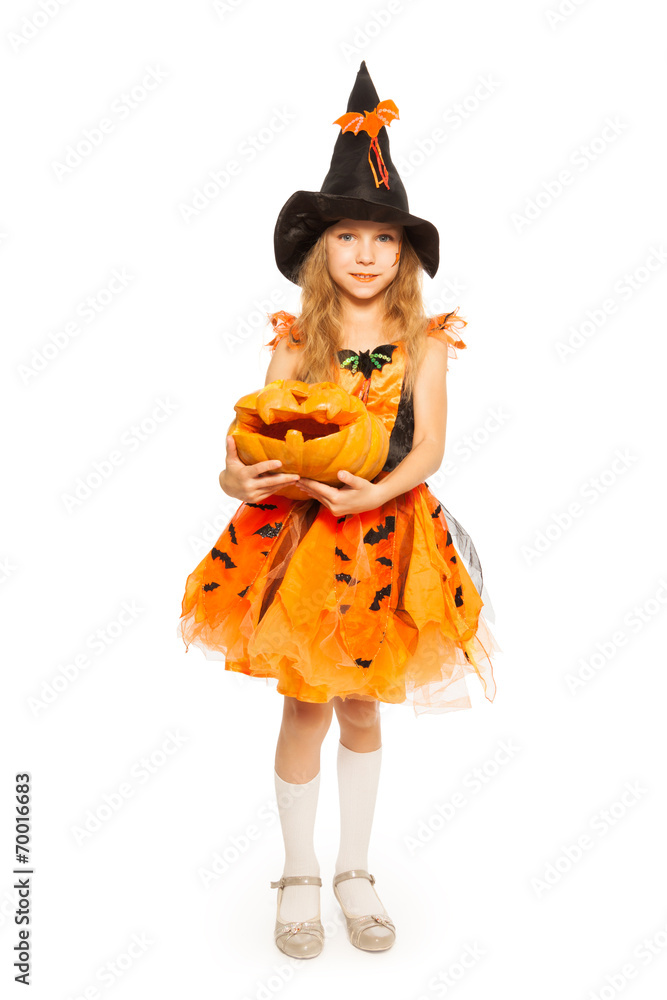 Girl in witch dress hold carved Halloween pumpkin