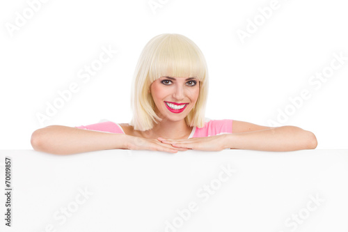 Smiling blonde leaning on a white banner