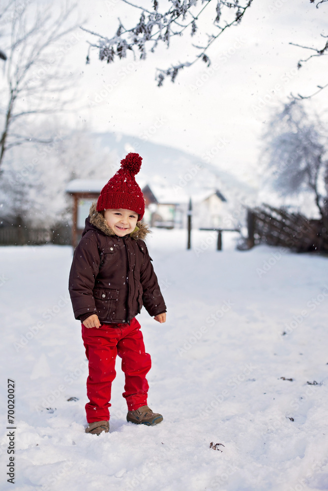 Portrait of child in brown jacket and red knitted hat and red tr