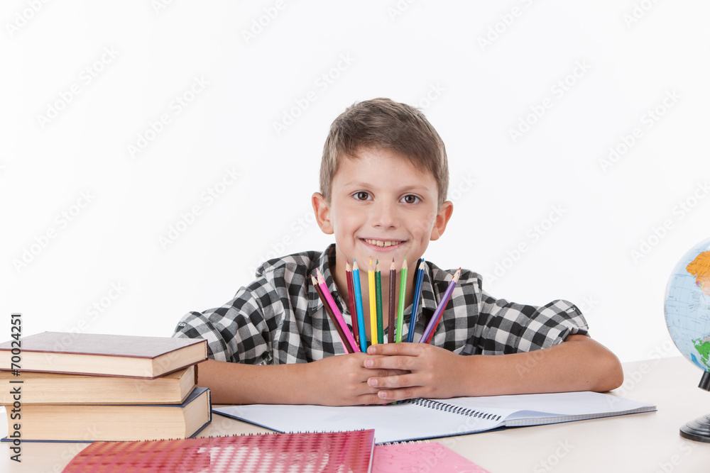 cute boy sitting at table and holding colorful pencils. cute boy sitting at table and holding colorful pencils.