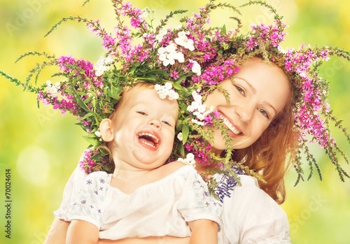 happy daughter hugging mother in wreaths of summer flowers