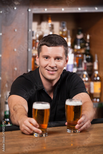 Bartender serving two glasses of beer.