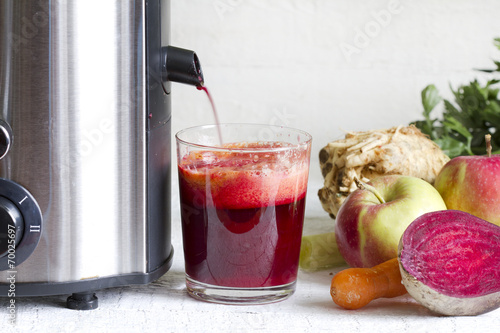 Juicer and juice with fresh fruits and vegetables photo