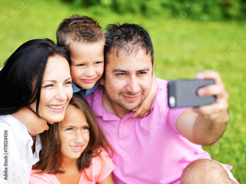 family taking selfies with smartphone in park