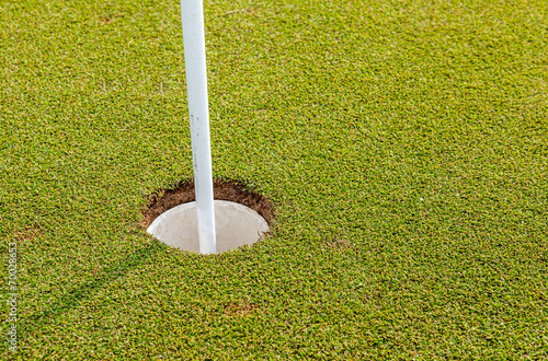Golf hole and flag on green grass of golf course