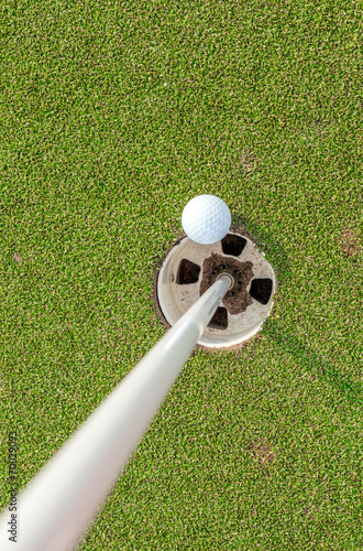 Aerial view of golf ball near pin and hole on green grass of gol