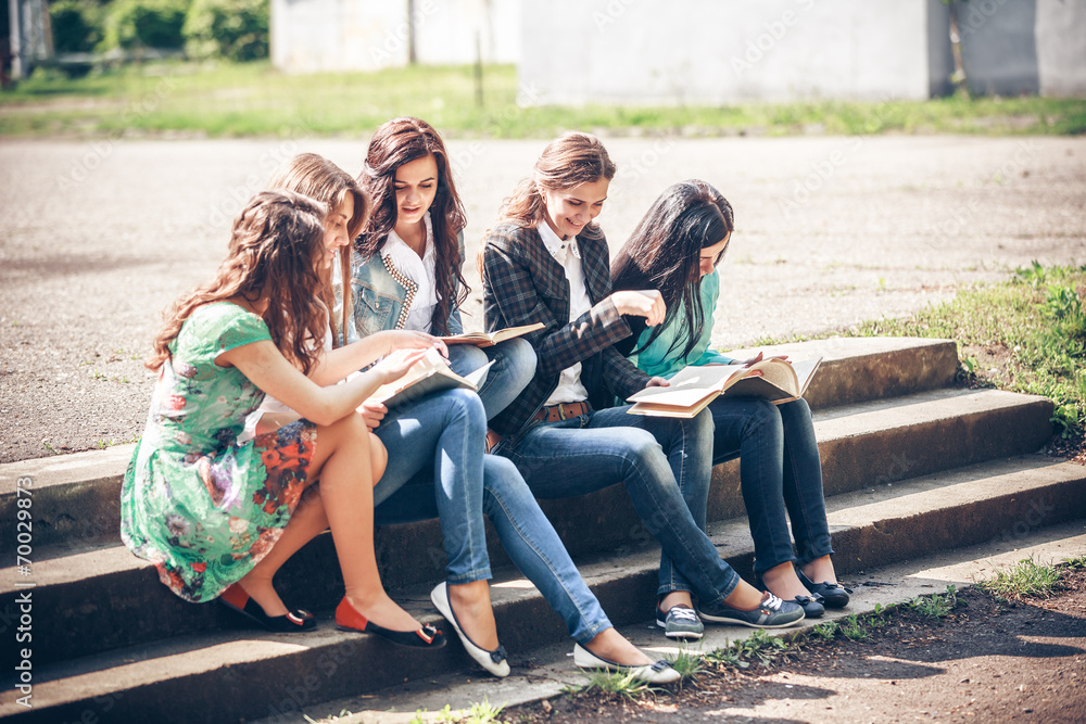 Group of students sitting with a books on street Group of students sitting with a books on street