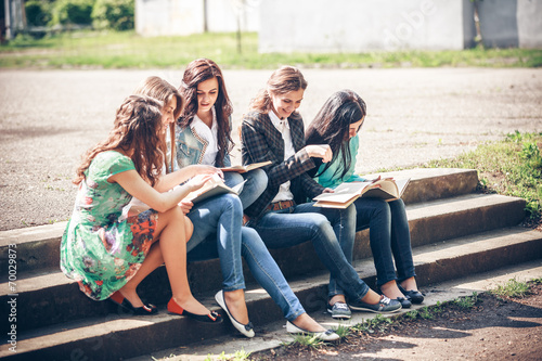 Group of students sitting with a books on street