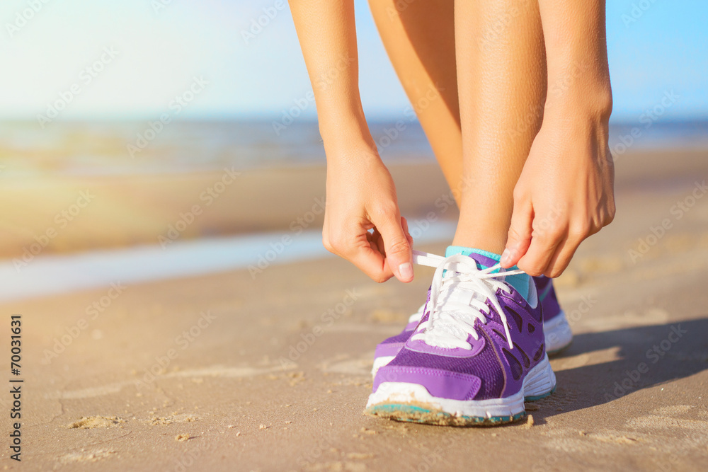 Woman wearing running shoes on the beach - obrazy, fototapety, plakaty 