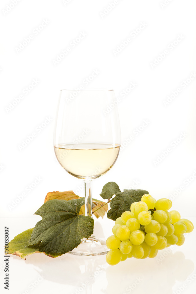 Weisswein im Glas mit Trauben vor weissem Hintergrund