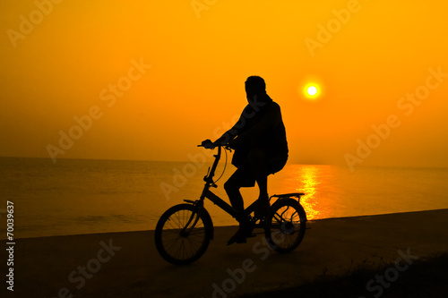 siluette of person who rides a bicycle near sea water with the s