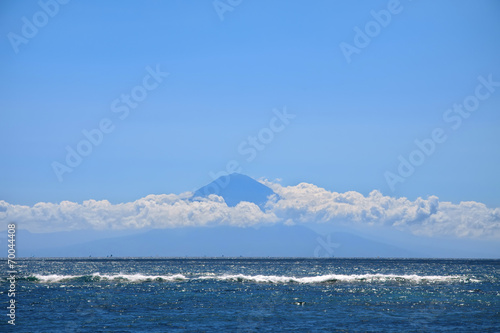 Fotografi Far away silhouette of a volcano above sea waters