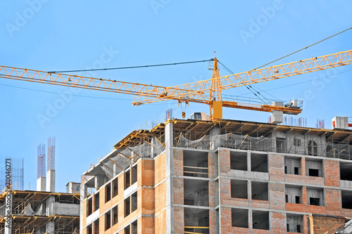 Crane and building construction site against blue sky