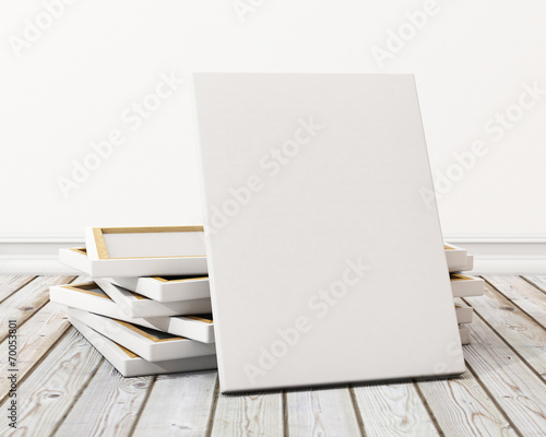 blank canvas or poster with pile of canvas on floor and wall