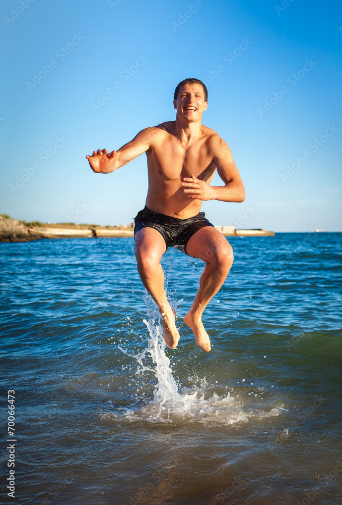 Fototapeta premium Young man jumping on the beach