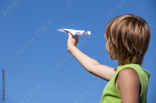 young boy with paper plane against blue sky