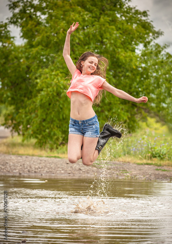 Fototapeta Naklejka Na Ścianę i Meble -  happy teen girl, jumps into a puddle
