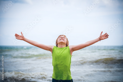 boy with raised hands on the seashore