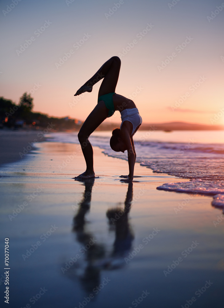 Fitness woman working out at the beach during sunrise