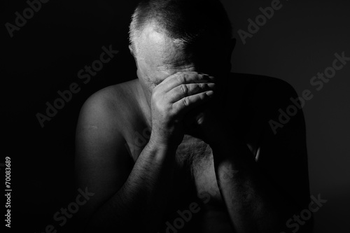 Sad man with hands on face over black