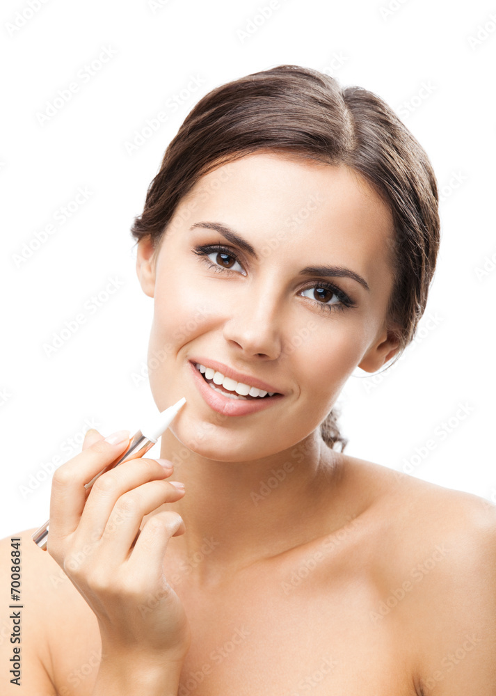 Smiling woman applying concealer on face, isolated Smiling woman applying concealer on face, isolated