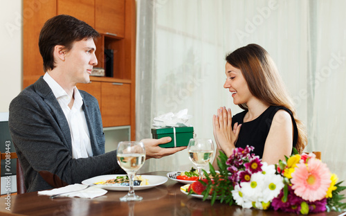 Man giving present to young woman during romantic dinner