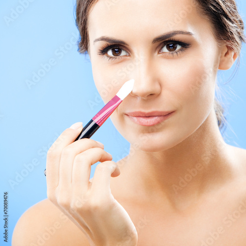 Woman with cosmetics brush, on blue