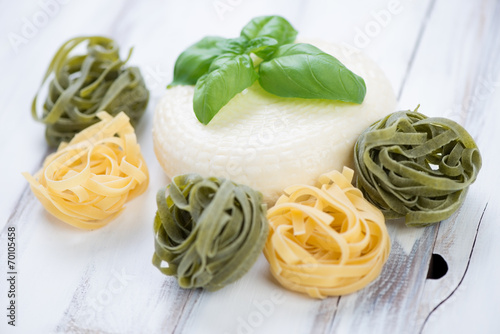 Round cheese with raw tagliatelle and fresh green basil