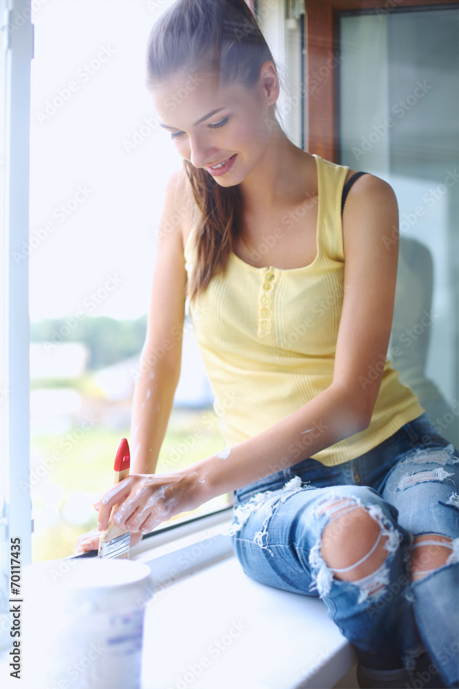Woman painting wall of an apartment with a paintbrush carefully Woman painting wall of an apartment with a paintbrush carefully