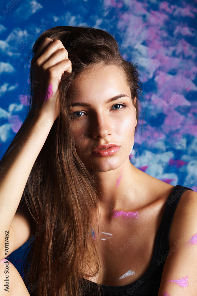 Young woman sitting near painting wall