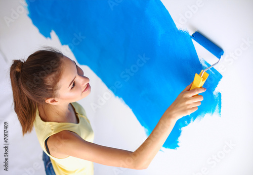 Happy beautiful young woman doing wall painting  standing on la