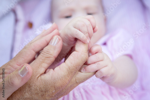 Grandmother hands holding baby hands